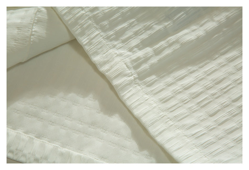 Close-up of a folded seam and textured fabric on the ivory shirt.