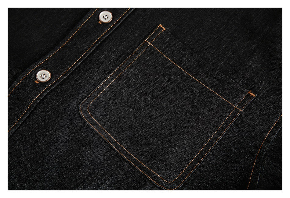 Close-up of a black denim shirt chest pocket beside its button placket, with tan stitching.