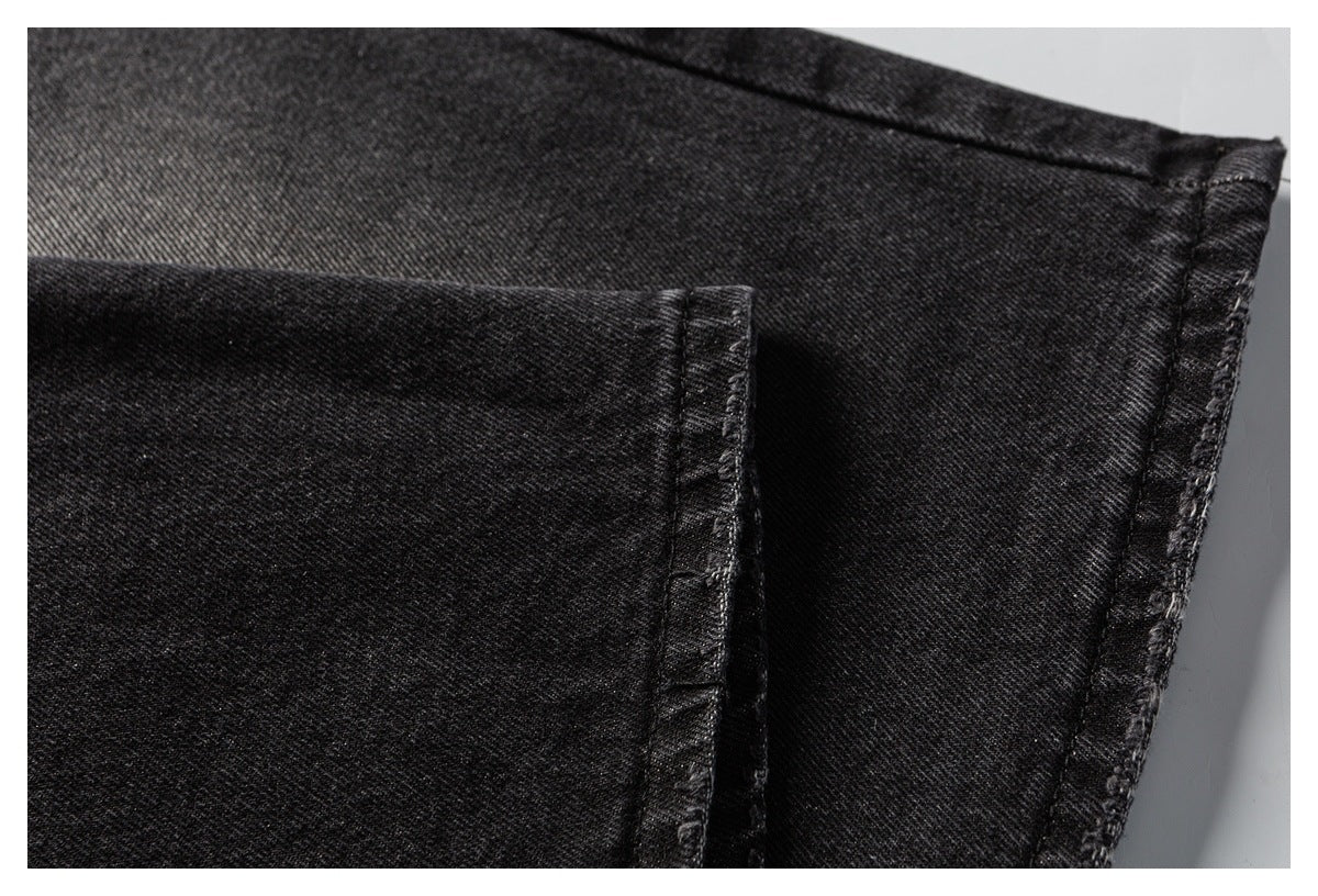 Close-up of black denim jeans showing a stitched hem and seam.