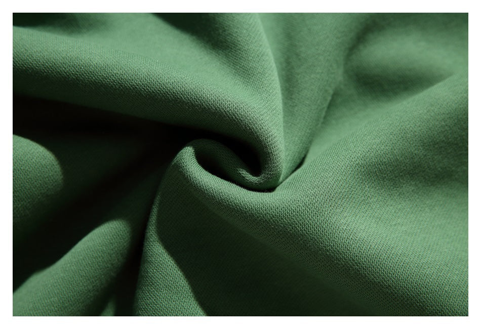 Macro view of the smooth green sweatshirt fabric gathered into folds.