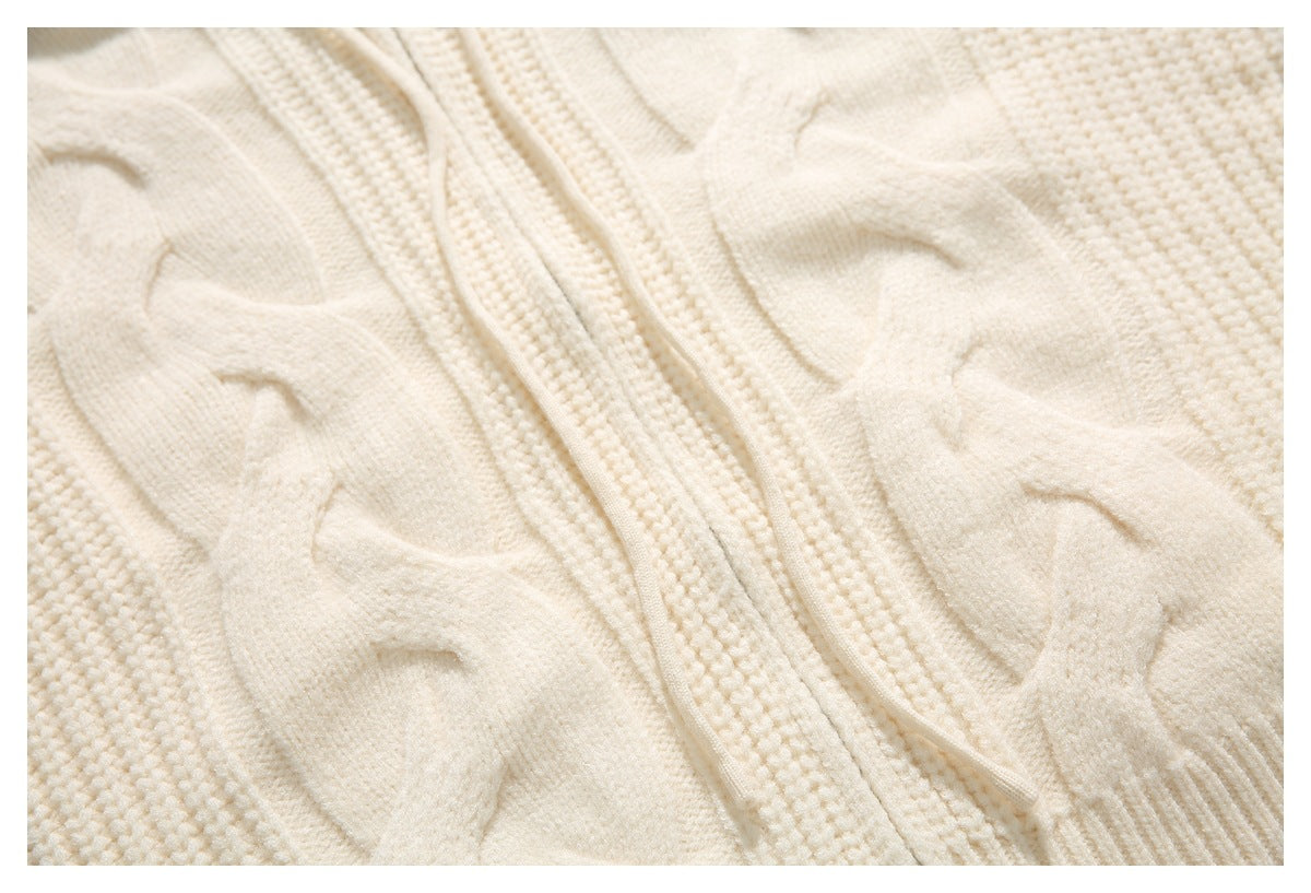 Close-up of raised cable-knit panels and the zipper placket on an ivory cardigan.