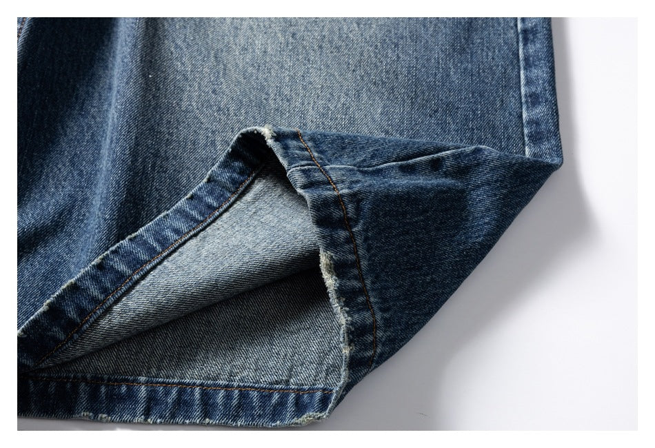 Close-up of a turned-up jean hem showing the lighter denim underside and seam stitching.