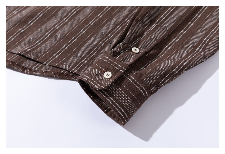 Close-up of a buttoned cuff on a brown shirt with narrow white stripes.