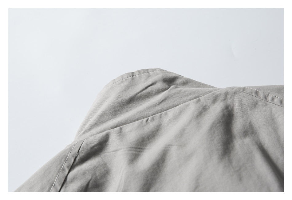 Close-up of curved shoulder and seam stitching on a light gray garment.