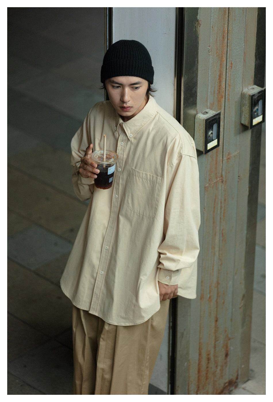 Model wearing an oversized cream button-up shirt with a chest pocket and beige trousers.