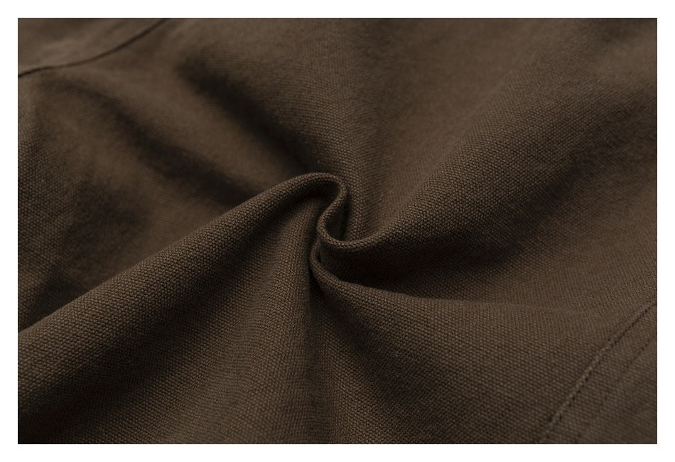Close-up of the brown trousers' woven-looking fabric gathered into a fold.
