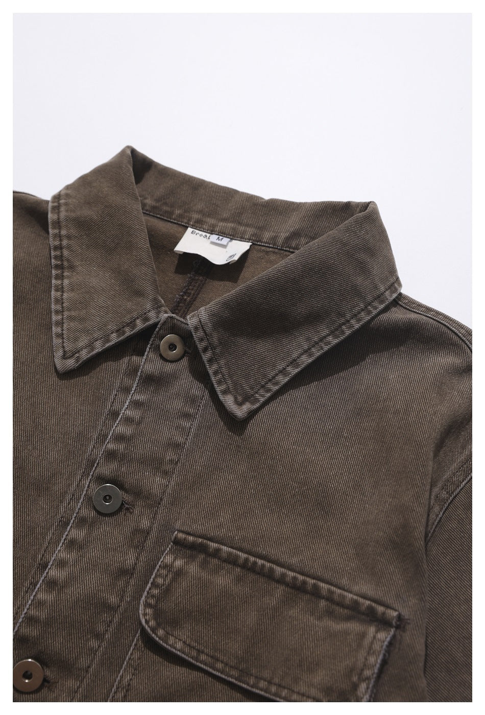 Close-up of a brown button-front shirt showing its pointed collar, chest pocket, and dark buttons.