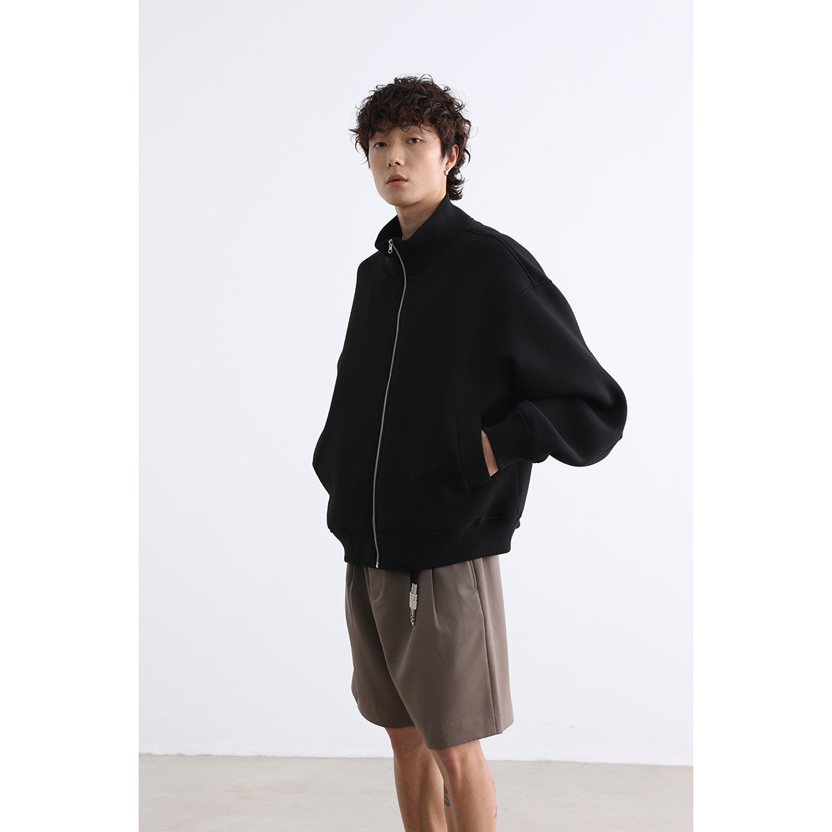 Model wearing a black zip-front jacket with a high collar, roomy sleeves, and ribbed cuffs and hem.