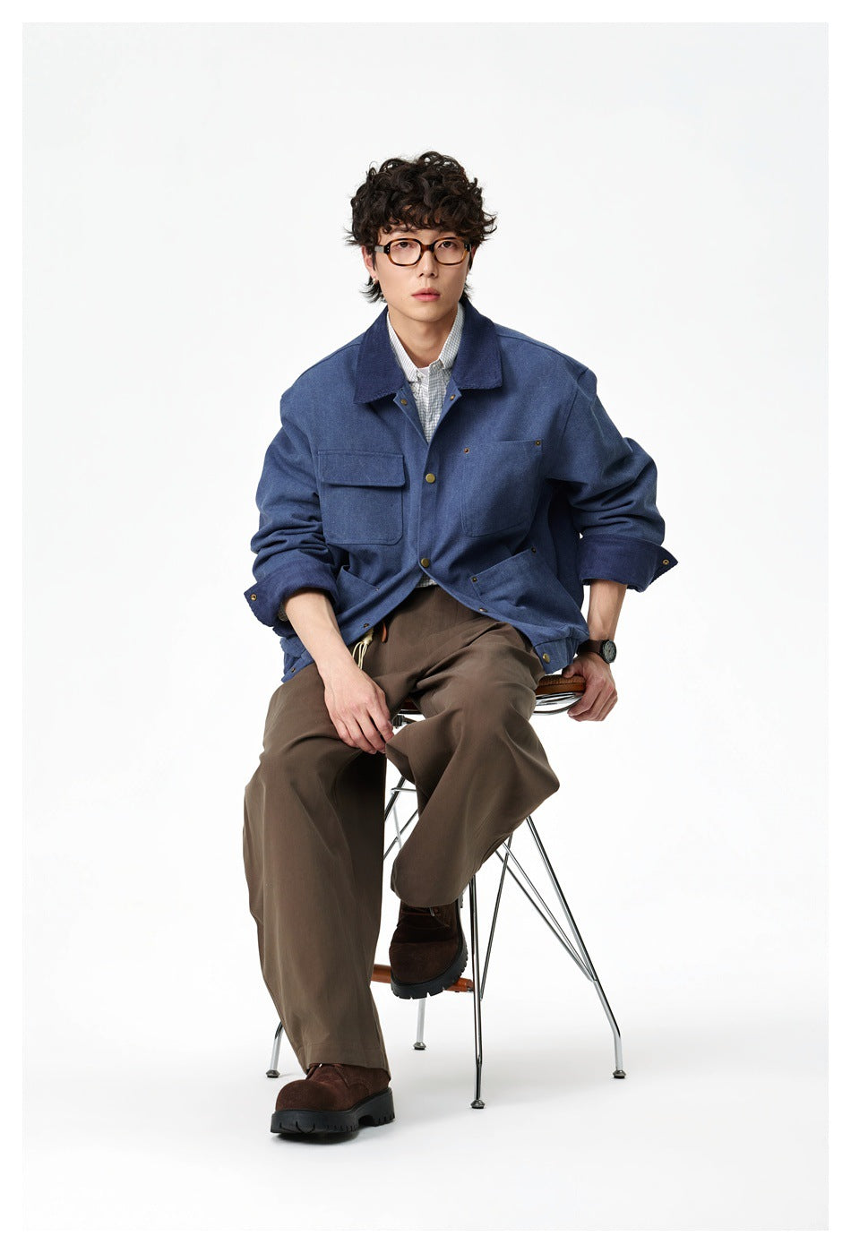 Full-length view of a seated man wearing the blue jacket with brown wide-leg pants and dark brown shoes