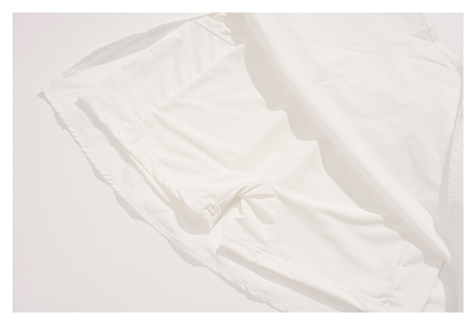 Close-up of the inside of a white garment, showing folded fabric, seams, and a narrow fabric tie.