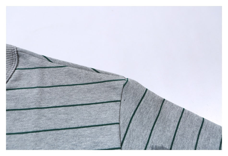 Close-up of a gray T-shirt shoulder and sleeve with narrow green stripes.