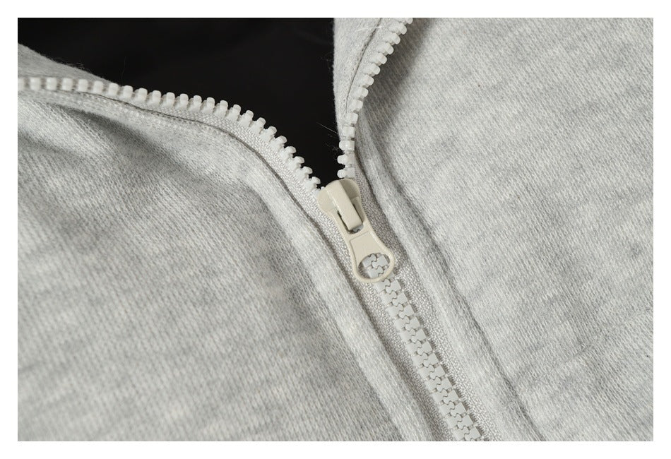 Close-up of a light gray garment with a chunky white zipper and ring-shaped pull.