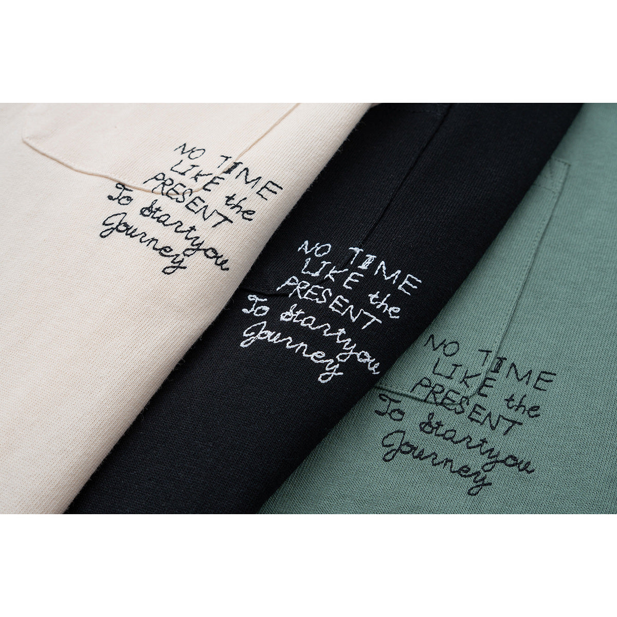 Close-up of cream, black, and sage green T-shirt fabric with the same handwritten English phrase on each.