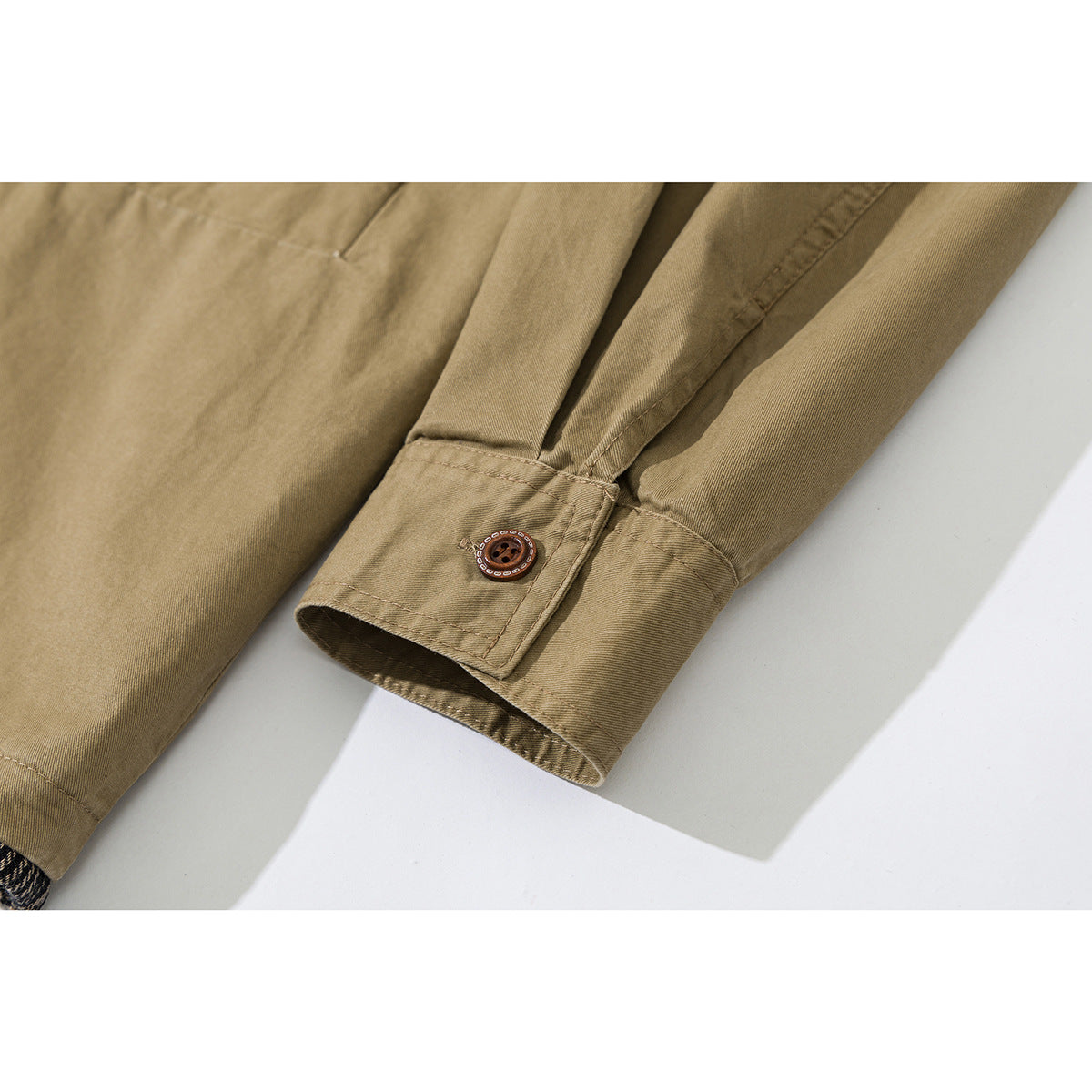 Close-up of a khaki jacket sleeve cuff with a decorative brown button and stitched placket.