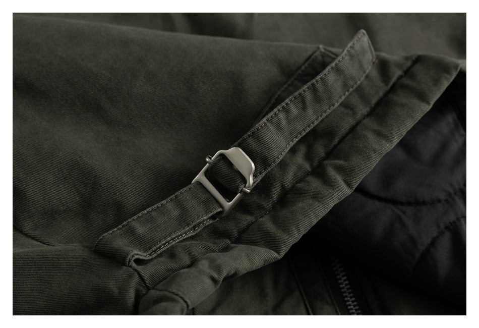 Close-up of a silver buckle strap on dark olive fabric beside a black zipper.