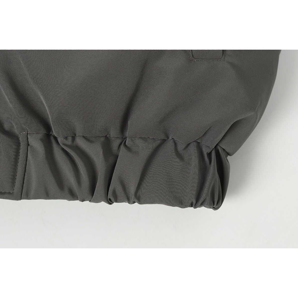 Close-up of the dark gray jacket's gathered elastic hem and seam.