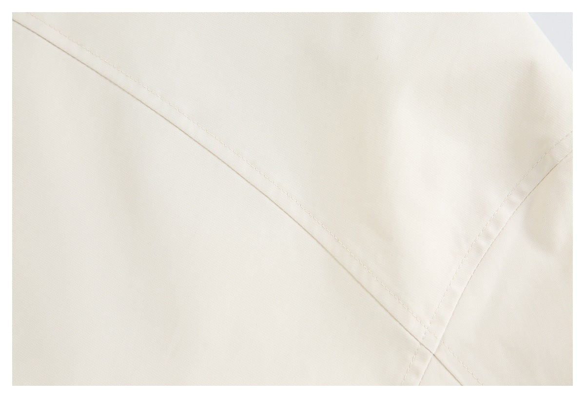 Close-up of ivory garment fabric with angled stitched seams and a folded panel.