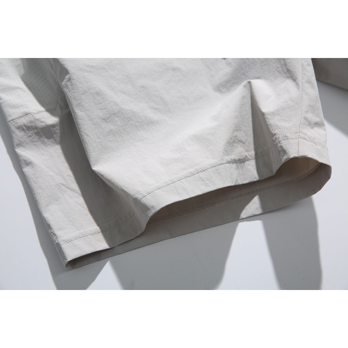Close-up of the white shorts' leg opening, showing the hem stitching and fabric.