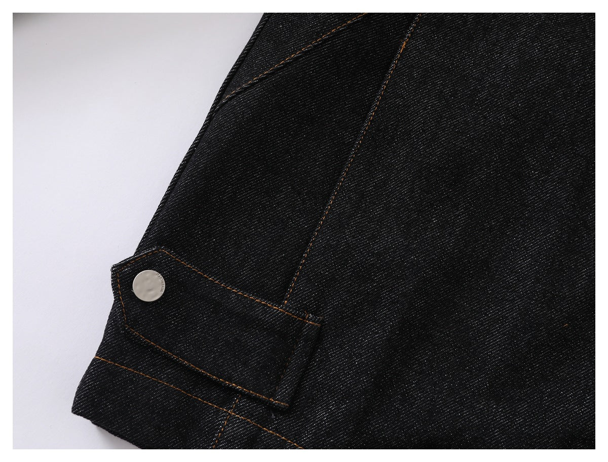 Close-up of dark denim with orange stitching and a silver snap fastener.