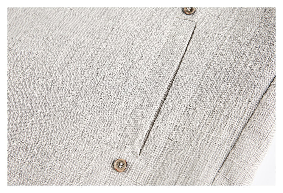 Close-up of a buttoned welt pocket on cream textured fabric.