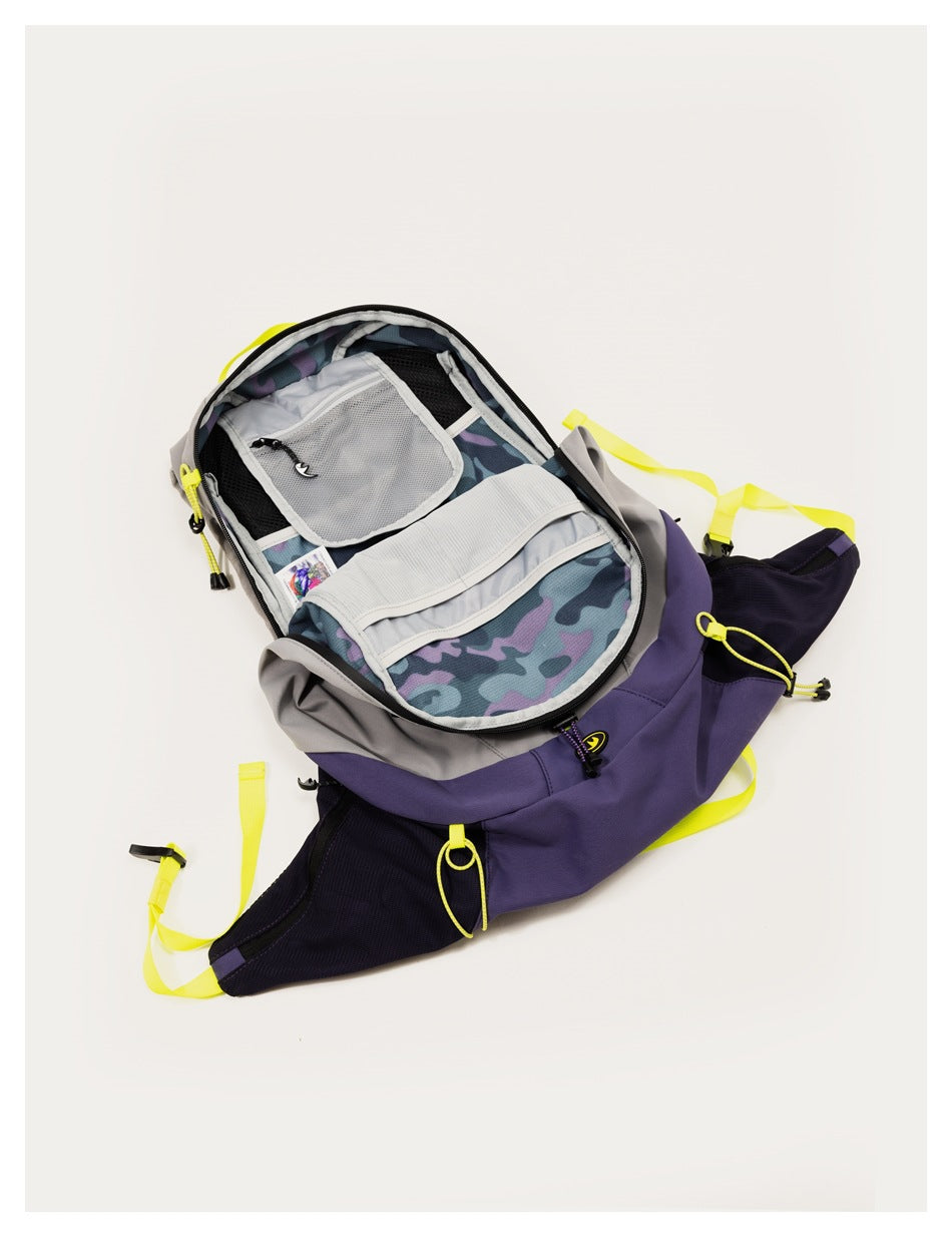 An open gray and purple backpack reveals mesh pockets, interior compartments, and a blue-purple camouflage lining.