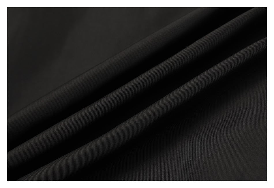 Close-up of black fabric arranged in soft folds, showing its fine surface texture.