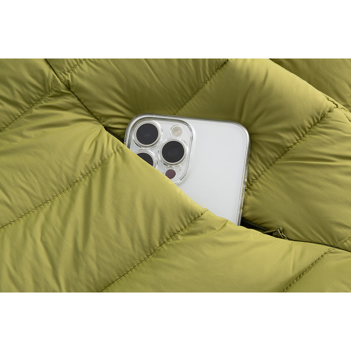 Close-up of a phone tucked into the pocket of an olive-green quilted jacket.