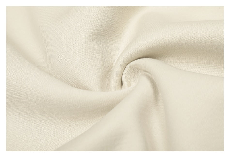 Close-up of off-white fabric draped into soft folds, showing its fine textured surface.