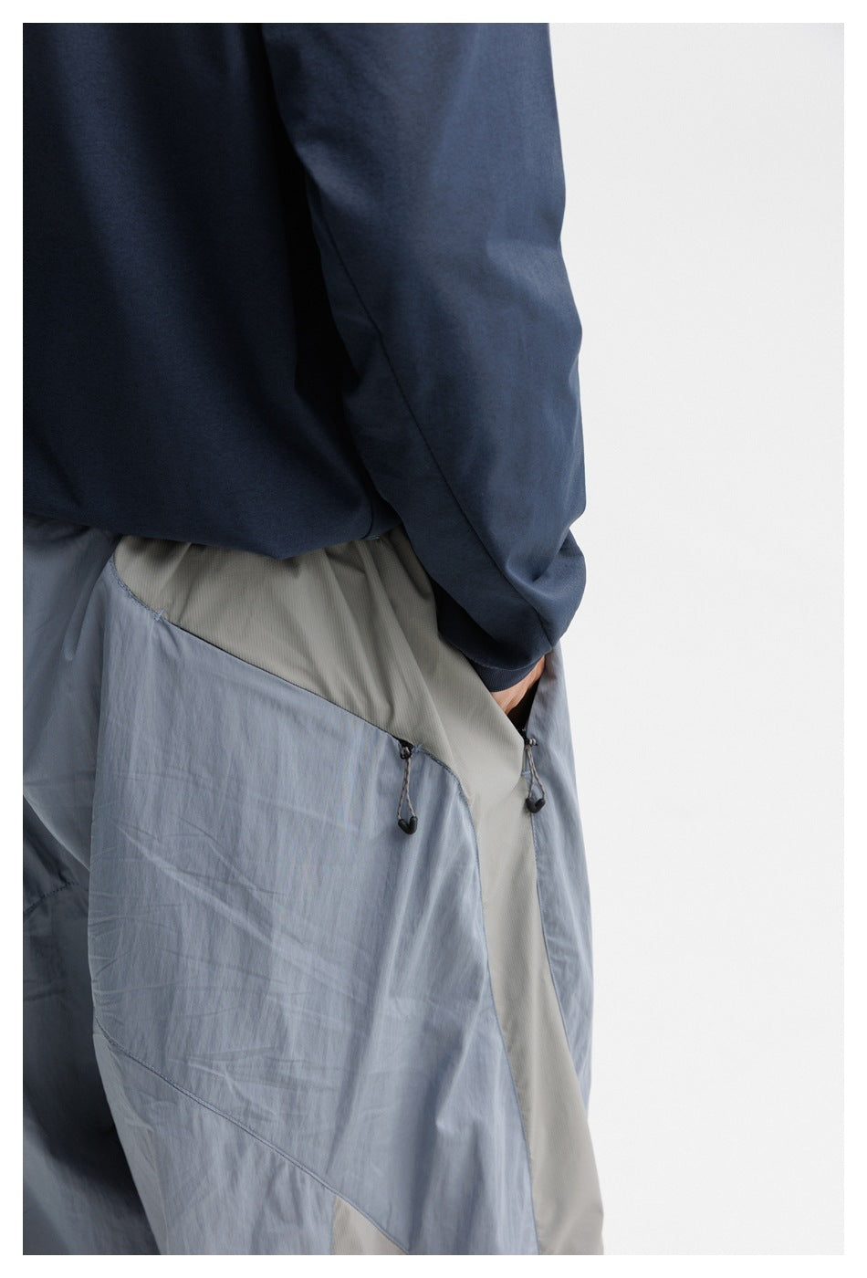 Close-up of the pants' waist and side pocket, with pale contrast fabric and adjustable drawcord toggles.