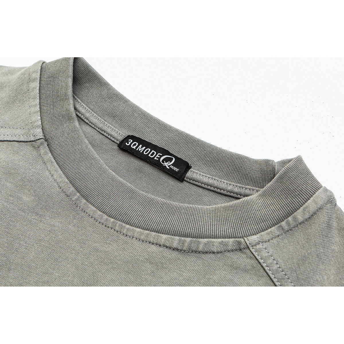 Close-up of a gray crewneck shirt’s ribbed collar, shoulder seam, and black neck label.