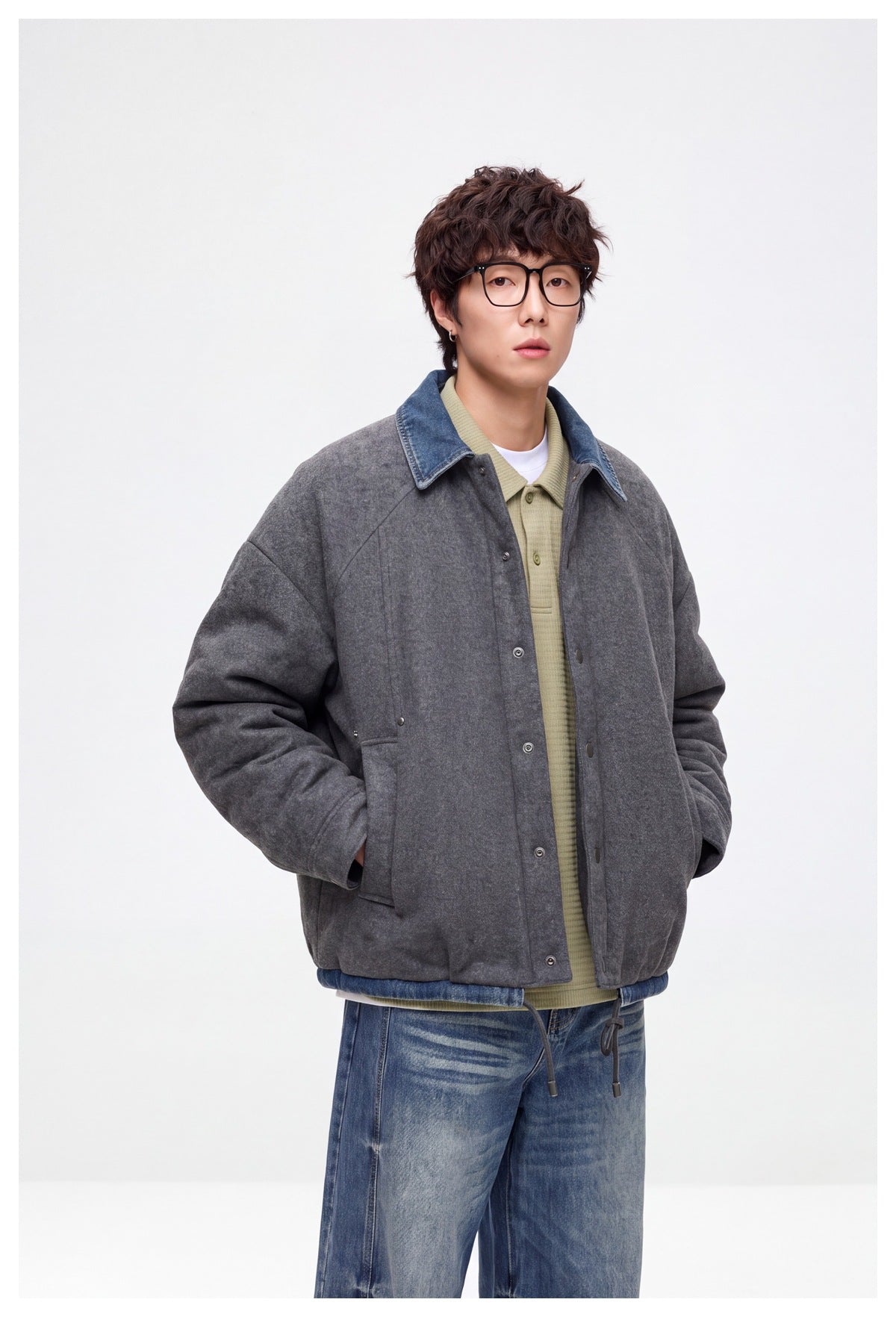 Closer view of a model wearing a charcoal-gray jacket with a blue denim collar and snap front.