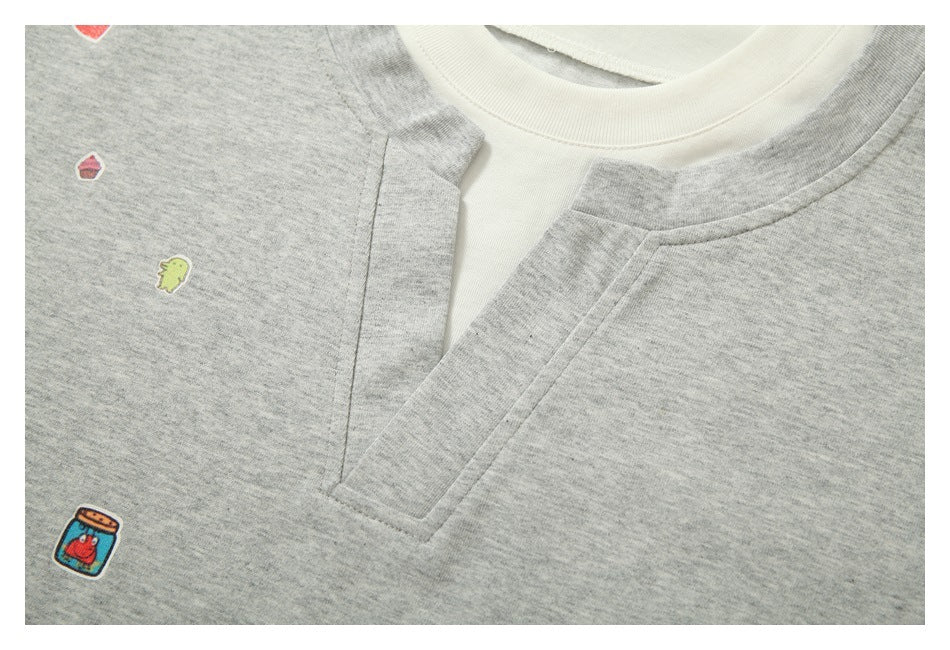 Close-up of the gray shirt's white crew neck and overlapping V-shaped front opening, with small colorful motifs.