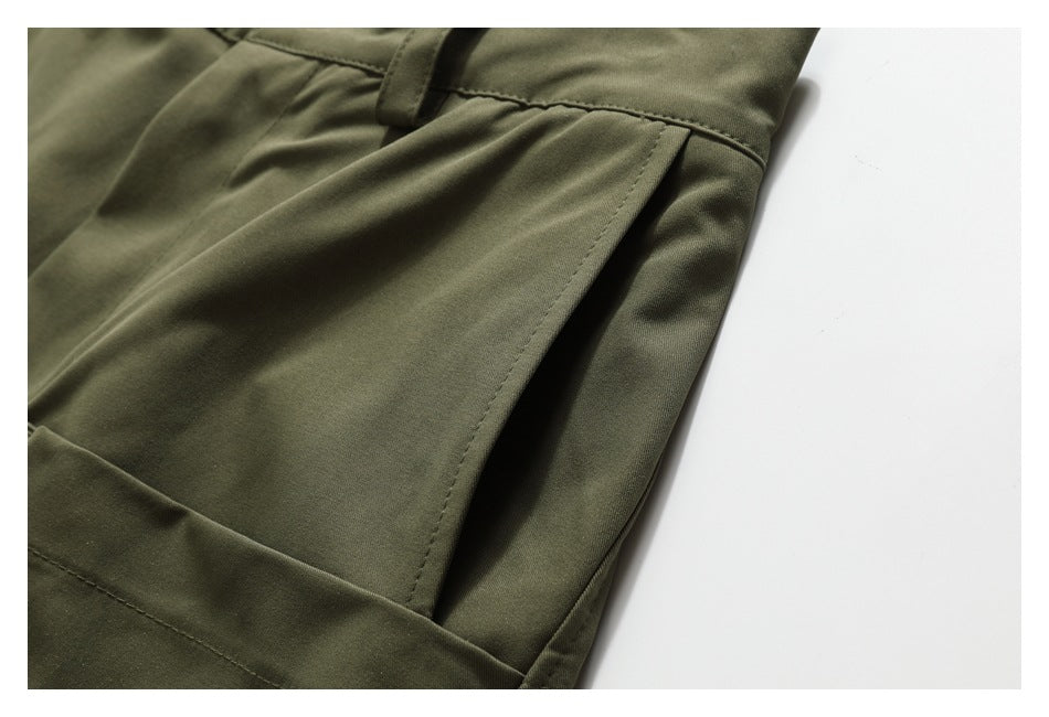 Close-up of olive-green trousers showing a side pocket opening and stitching.