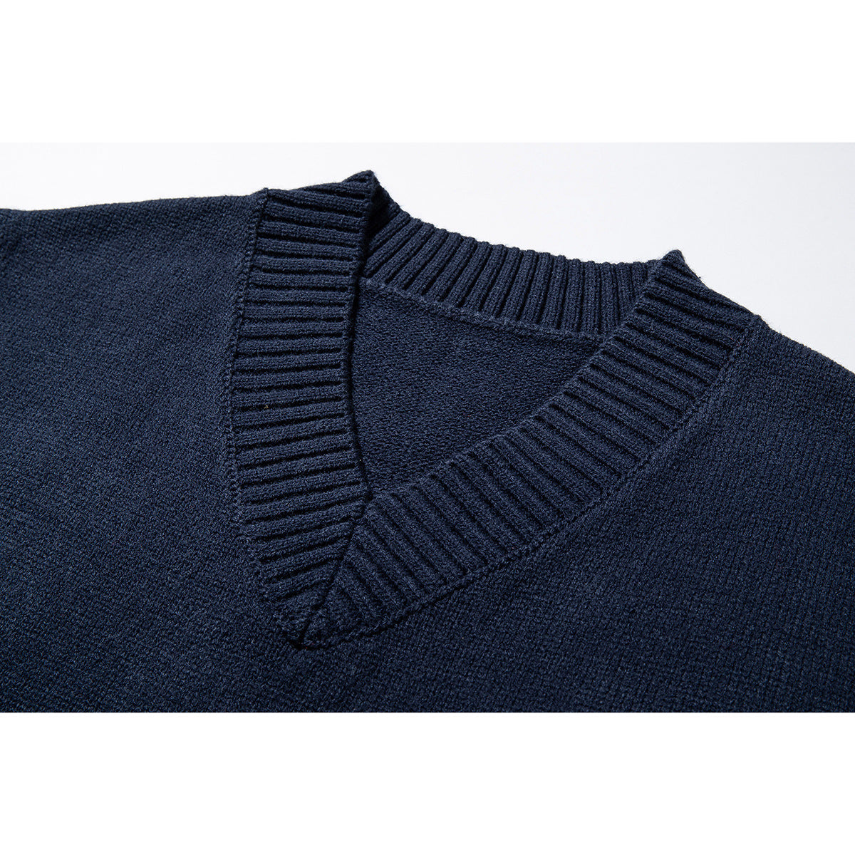 Close-up of the ribbed V-neck trim and knit texture on a dark navy sweater vest.