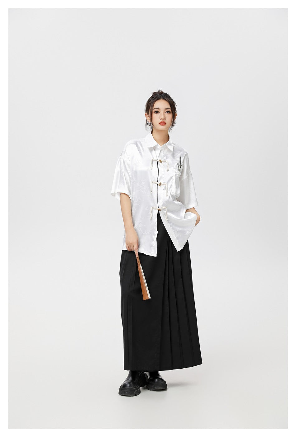 Full-length model wearing a white patterned frog-closure shirt with a long black skirt and boots.