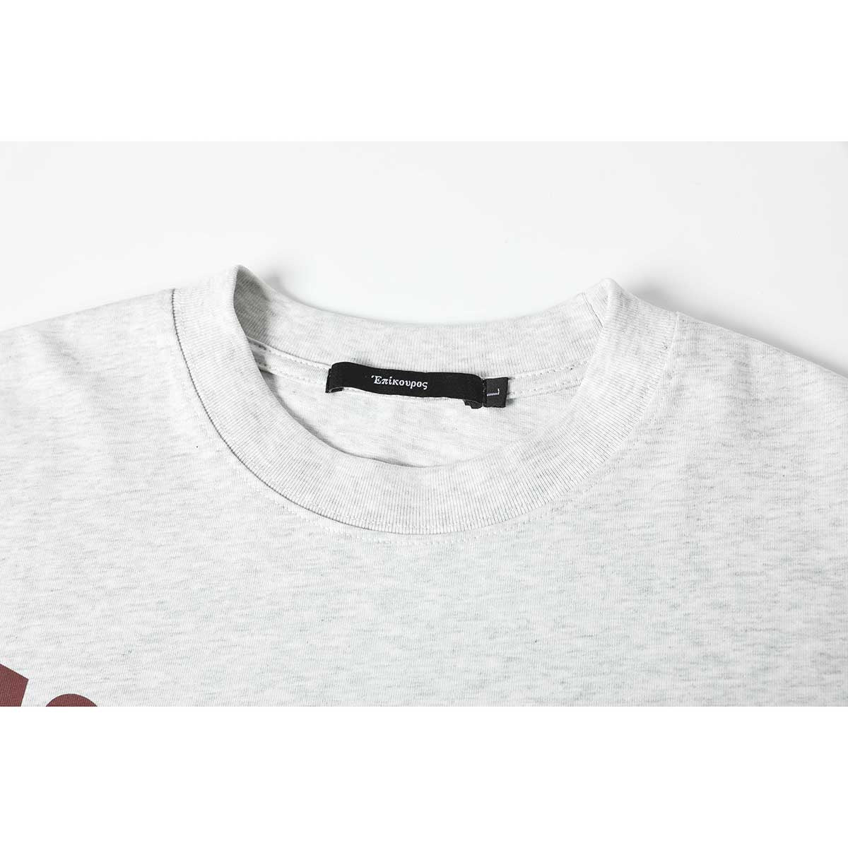 Close-up of a light gray melange T-shirt's crew neckline and black sewn-in label.