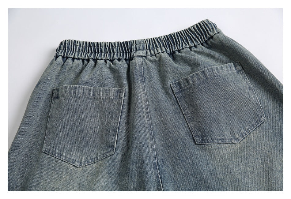 Close view of the back of gray-blue denim pants with an elastic waistband and two patch pockets, laid flat.