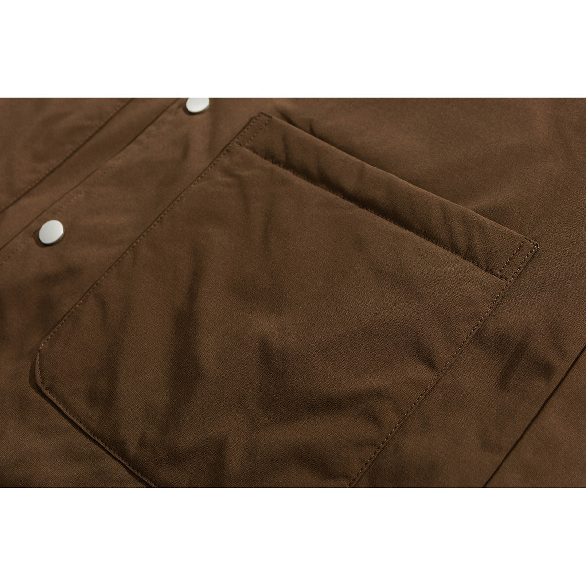 Close-up of a large stitched pocket on a brown jacket.