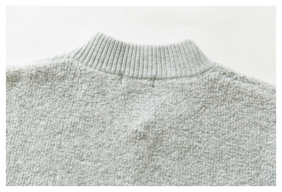 Close-up of the ribbed collar and textured upper back of a light gray knit sweater.