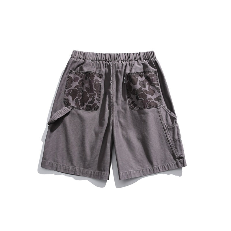 Rear view of charcoal gray shorts with an elastic waistband, camouflage-print patch pockets, and side cargo pockets.