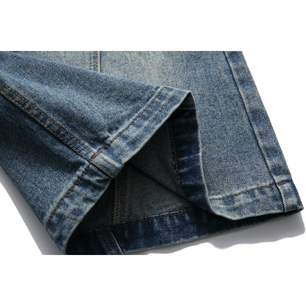 Close-up of a blue washed jeans leg hem, with the folded cuff and inside stitching visible.