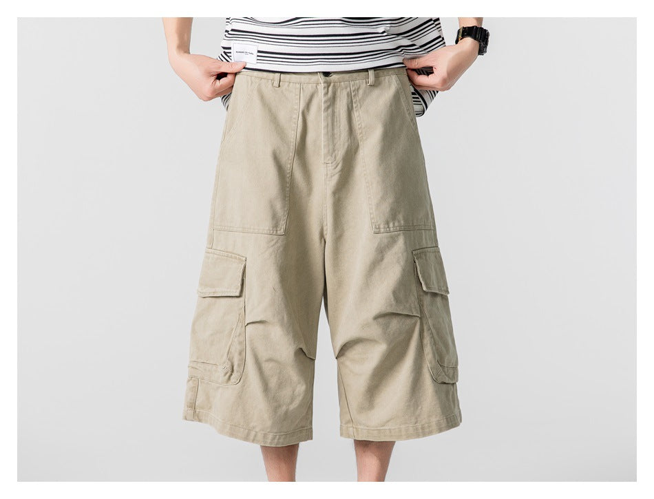 Front view of loose beige cargo shorts worn by a model, with large flap pockets on both sides.