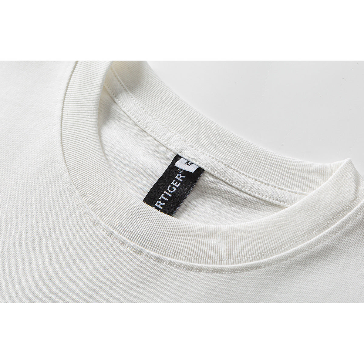 Close-up of a white T-shirt crew neckline and black woven neck label.
