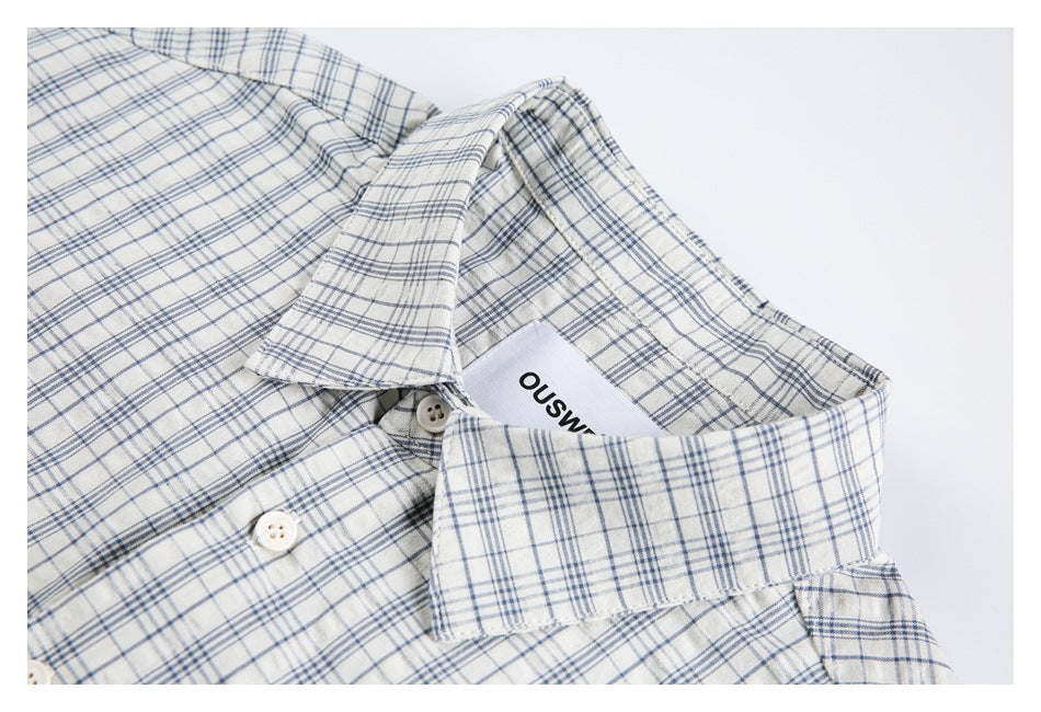 Close-up of the shirt's plaid collar, neckline label, and white buttons.
