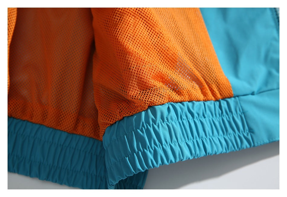 Close-up of turquoise garment hem with gathered elastic trim and bright orange mesh lining.