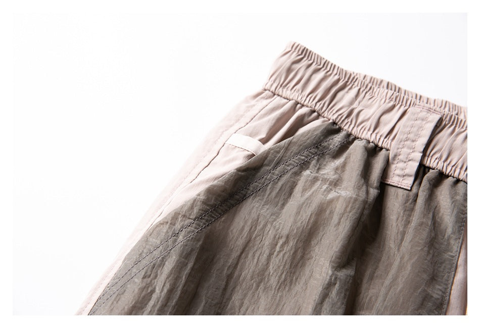 Close-up of the shorts’ elastic waistband and stitched seam joining pale beige fabric with crinkled gray panels.