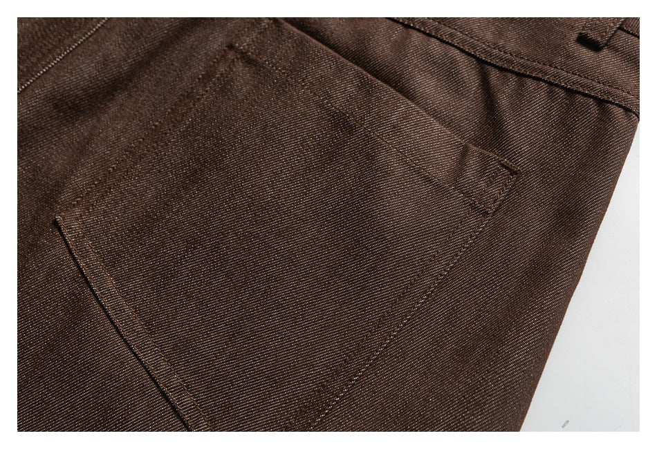 Close-up of a stitched pocket on dark brown trousers with visible diagonal fabric texture.