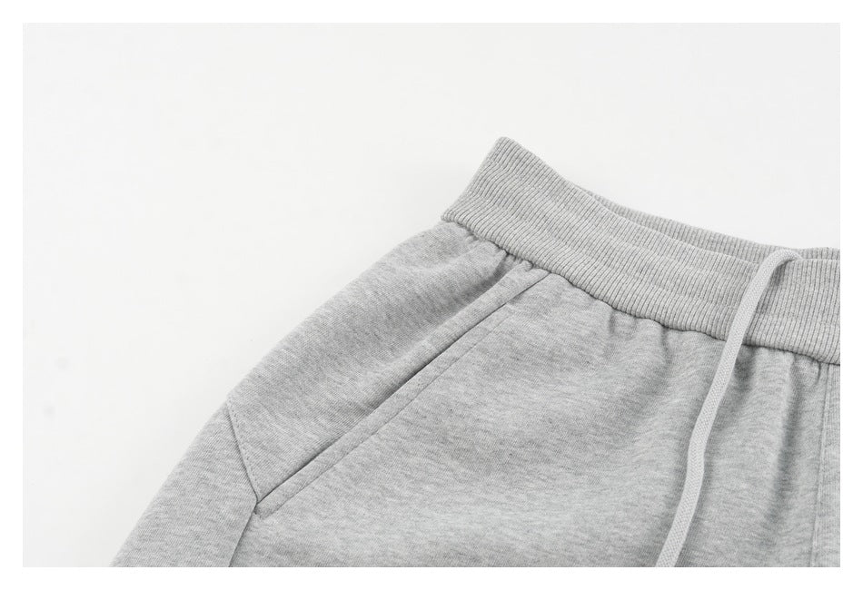 Close-up of a light gray sweatpants waistband, drawstring, and angled side pocket.