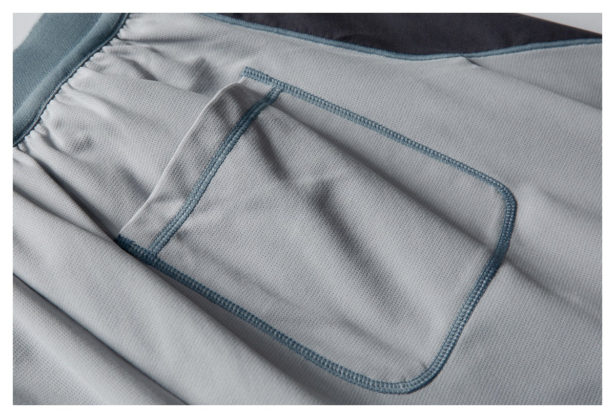Close-up of a rectangular pocket with blue-gray stitching on light gray textured fabric.