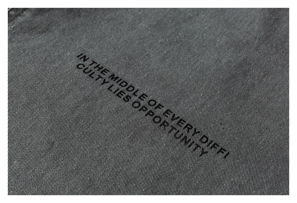 Close-up of gray fabric with the black printed phrase, “The middle of every difficulty lies opportunity.”